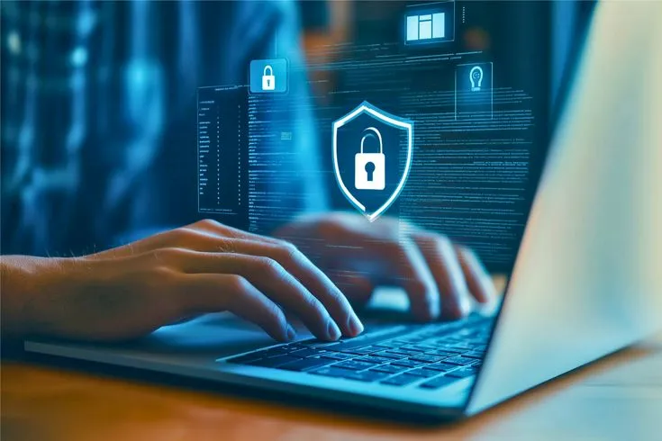 セキュリティの盾アイコンが表示されたノートパソコンを操作する手元
